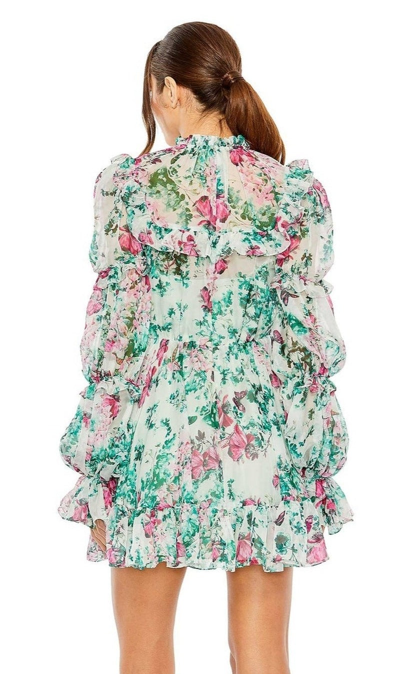 A woman with brown hair in a ponytail faces away from the camera, wearing the High-Neck Print Party Dress 56008 by Mac Duggal—a short, long sleeve party dress with pink and green ruffled floral print.